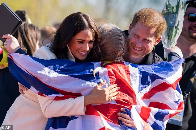 Prince Harry and Meghan Markle, Duke and Duchess of Sussex, hug Lisa Johnston, a former army medic and amputee, who celebrates with her medal at the Invictus Games venue in The Hague, Netherlands, Sunday, April 17, 2022